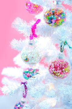 a white christmas tree with ornaments on it and candy in the bottom right hand corner