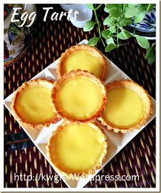 four lemon tarts sitting on top of a white plate next to a potted plant