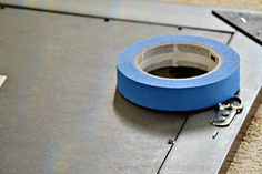 a roll of blue tape sitting on top of a piece of metal with two keys attached to it