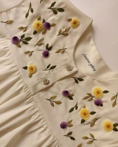 a white dress with yellow and purple flowers on it