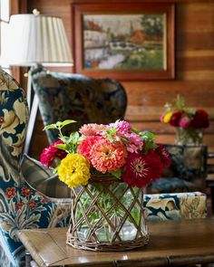 a vase filled with colorful flowers sitting on top of a table next to a chair