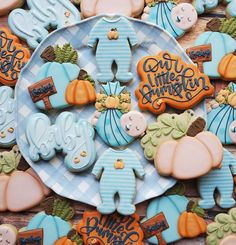 baby shower cookies are on a plate with blue and orange decorations in the shape of pumpkins