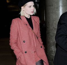 a woman with blonde hair wearing a red and black coat