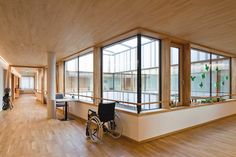 an empty room with wooden flooring and large windows on the wall, along with wheelchairs