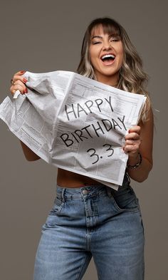 a woman is holding up a newspaper with the words happy birthday on it and laughing