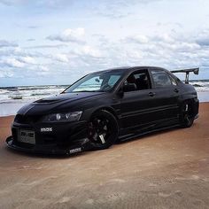 a black car parked on top of a sandy beach