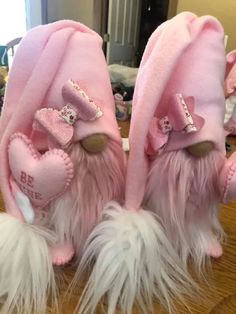 two stuffed animals wearing pink hats on top of a wooden table