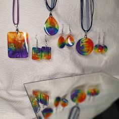 a collection of colorful jewelry is displayed on a white tablecloth with a mirror in the foreground