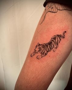 a black and white tiger tattoo on the right arm, with a bird flying above it