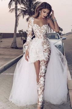 a woman in a white dress standing next to a car