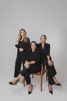 three women sitting on a chair posing for the camera