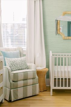 a baby's room with a chair, crib and mirror on the wall