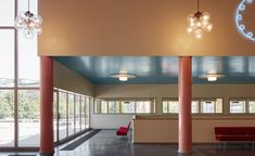 the inside of a building with large windows and red benches in front of it,