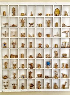 a white shelf filled with lots of gold items