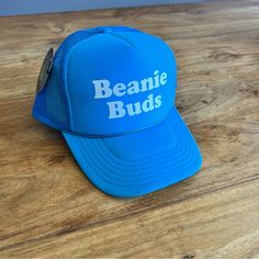 Beanie Buds Graphic Bright Blue Color Adjustable Terry Band On Interior Of Hat Trucker Style Designed By Rad Hats Los Angeles Blue Letter Print Trucker Hat For Beach, Trendy Blue Snapback Hat, One Size Fits Most, Blue Adjustable Trucker Hat With Short Brim, Blue Snapback Hat With Letter Print, Blue Letter Print Snapback Hat, Light Blue Snapback Hat, Adjustable Blue Beanie Hat, Blue Snapback Hat With Letter Print And Curved Brim, Spring Blue Trucker Hat With Letter Print