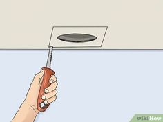 a hand holding a remote control in front of a ceiling fan with the light on