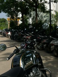 a row of motorcycles parked next to each other on a sidewalk in front of trees