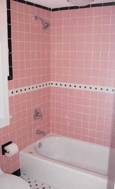 a bathroom with pink tiles on the walls and floor, including a white toilet next to a bathtub