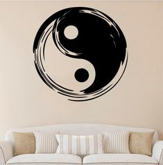 a living room with a white couch and black yin - yang symbol on the wall