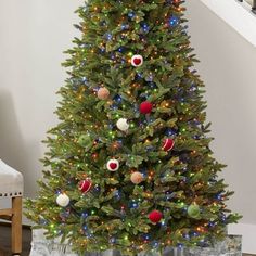 a decorated christmas tree in a living room next to a stair case with presents on it