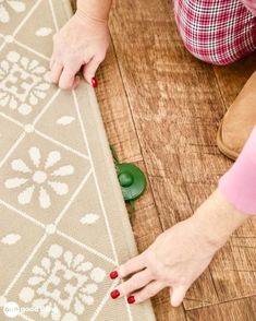 a woman laying on the floor with her hands on top of an area rug that is being laid out