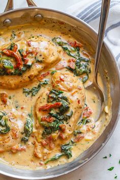 a pan filled with chicken and spinach covered in sauce