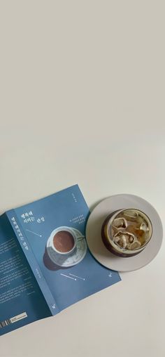 an open brochure sitting on top of a table next to a cup and saucer