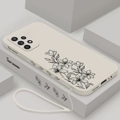 an iphone case with flowers on it sitting next to some boxes and packaging material for the phone