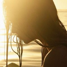 a woman is standing in the water with her hair blowing back and looking into the distance