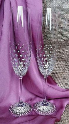 two wine glasses sitting next to each other on a purple cloth