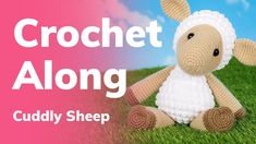 a crochet sheep sitting on top of a green grass covered field next to a pink and blue sky