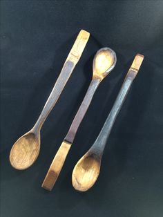 three wooden spoons are sitting next to each other on a black tablecloth surface