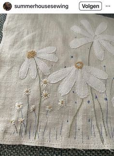 an embroidered pillow with white daisies on it