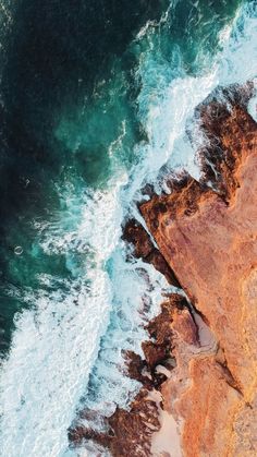 an aerial view of the ocean and rocks