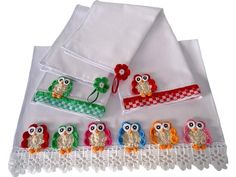 an assortment of colorful owls sitting on top of a white table cloth with red, green, yellow and blue flowers