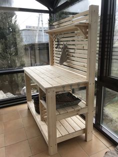 a table made out of wooden pallets on top of a tiled floor next to a window