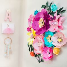 colorful paper flowers are hanging on the wall next to a clock and nameplates