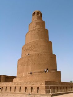 a tall brick structure with people standing on it's sides in front of a blue sky