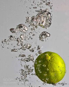 an orange falling into the water with bubbles