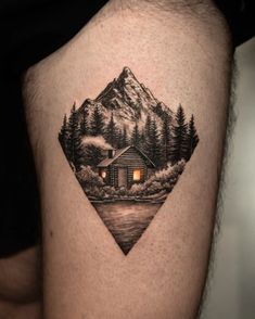 a man's thigh with a cabin in the woods and mountains tattoo on it