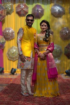 a man and woman standing next to each other in front of some balloons on the ground