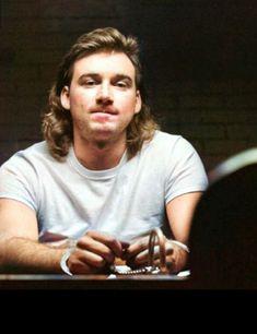 a man with long hair sitting at a table