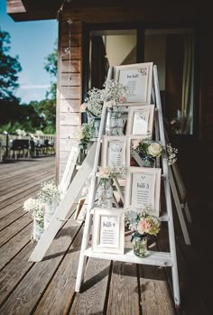 a white ladder with pictures on it and flowers in vases sitting next to each other