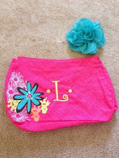 a pink purse with flowers on it and a blue flower sitting next to the letter l