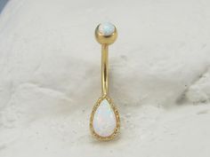 an opal belly button ring in gold with a white stone on the top and bottom