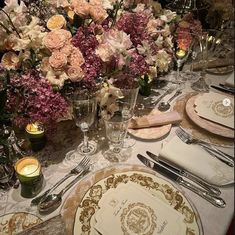 the table is set with plates, silverware and flowers