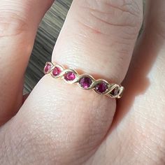 a woman's hand with a gold band and three pink stones on it,