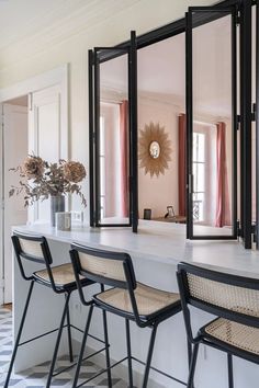 three chairs are sitting in front of a counter with mirrors on the wall above it