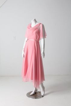 "This is a 1970s pink chiffon dress.  The airy dress features a pink slip dress with chiffon overlay with handkerchief hem, draped neckline, and flutter sleeves with ties at the shoulder. Slender ribbon belt at the waist.  CONDITION In good condition with wear consistent with age and use.  MARKED SIZE:  9/10 APPROXIMATE FIT: Small MEASUREMENTS Bust:  33\"  ..  83.8 cm Waist:  26\"  ..  66 cm Length*:  48\"  ..  121.9 cm Center Skirt Length:  39\"  ..  99.1 cm *From shoulder to hem on side.  8205 Dress With Chiffon Overlay, 70s Fashion Women, Pink Chiffon Dress, Pink Slip Dress, Handkerchief Hem Dress, Airy Dress, Handkerchief Dress, Chiffon Overlay, Ribbon Belt