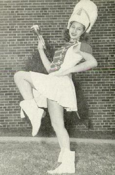 an old photo of a woman holding a tennis racquet in front of a brick wall